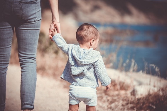 mother holding toddler's hand while walking on the beach, child custody attorney holtz law